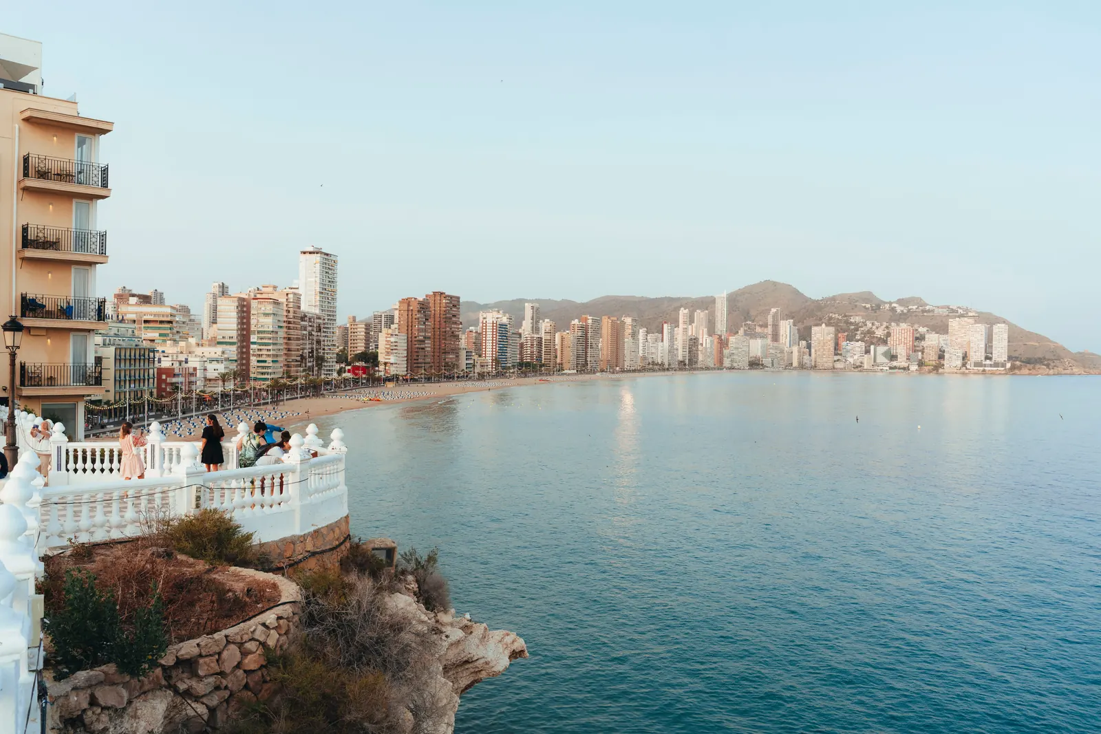A white stone balustrade viewpoint above the sea, with Levante beach and the tower blocks beyond
